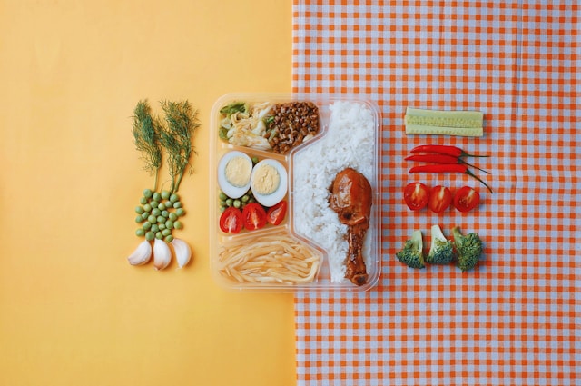 Une image de bento bien compartimenté avec des légumes et du riz posé sur une table