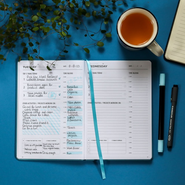 Un agenda ouvert sur un bureau avec une tasse de thé et des fleurs